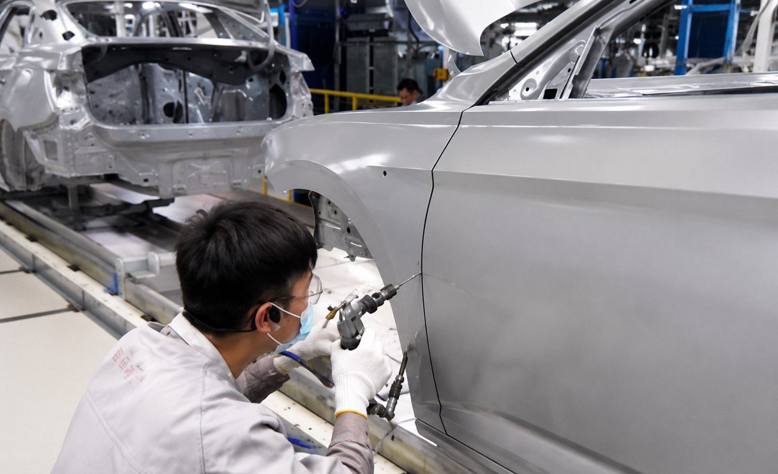 Technician applying seam sealer glue in automotive production and repair shop